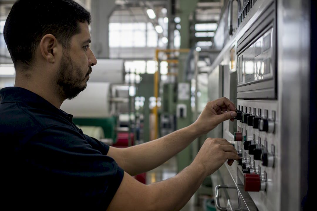 Manos ajustando los controles de una máquina textil