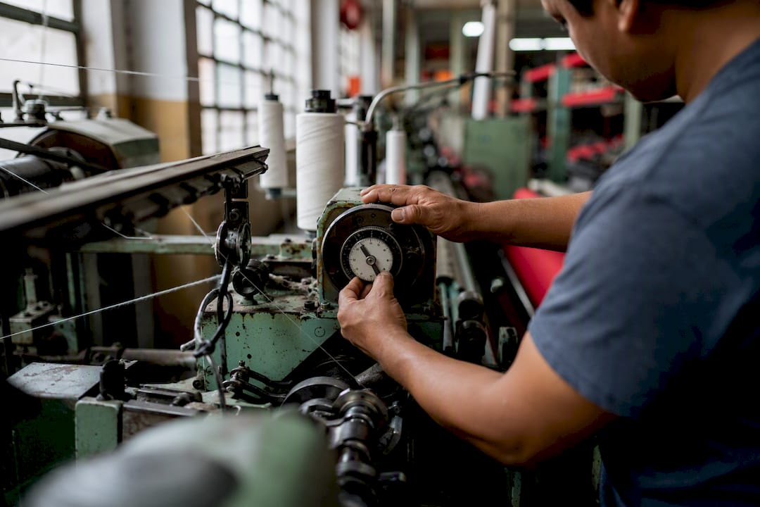 Manos ajustando los controles de una máquina textil
