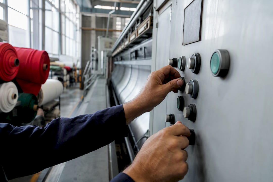 Manos ajustando los controles de una máquina textil